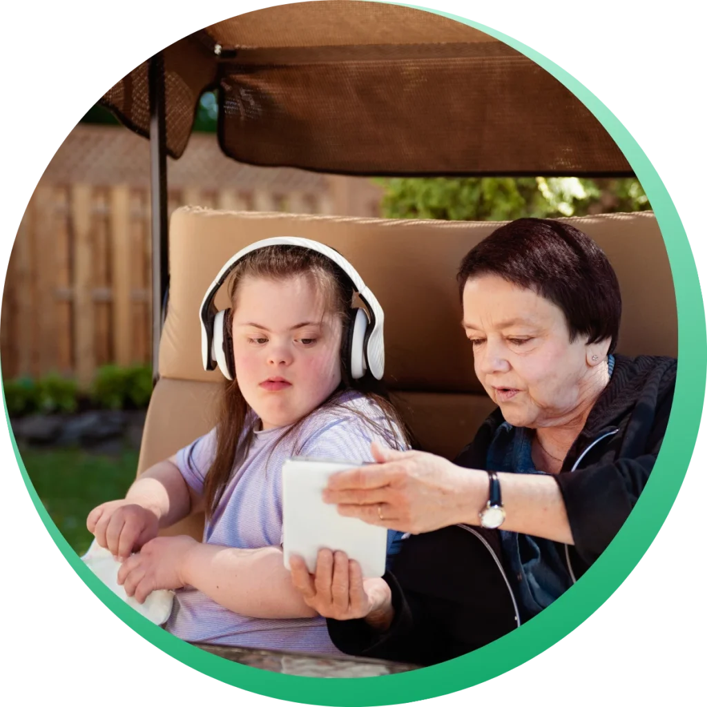 A woman showing her phone to a young girl with down syndrome